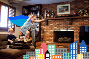 Imaginative play as a superhero, boy with cape jumping over buildings